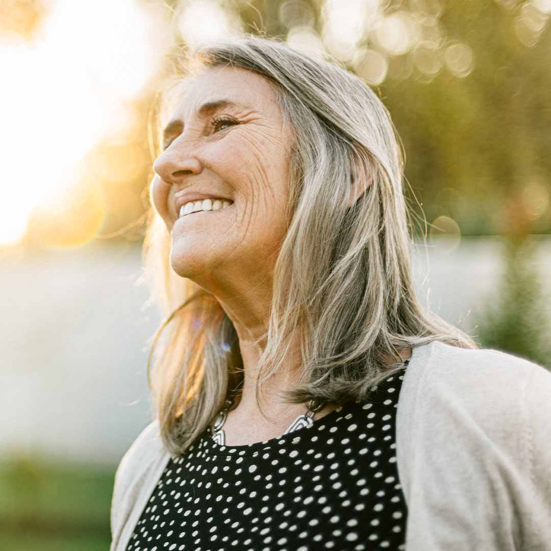 older woman smiling in her backyard